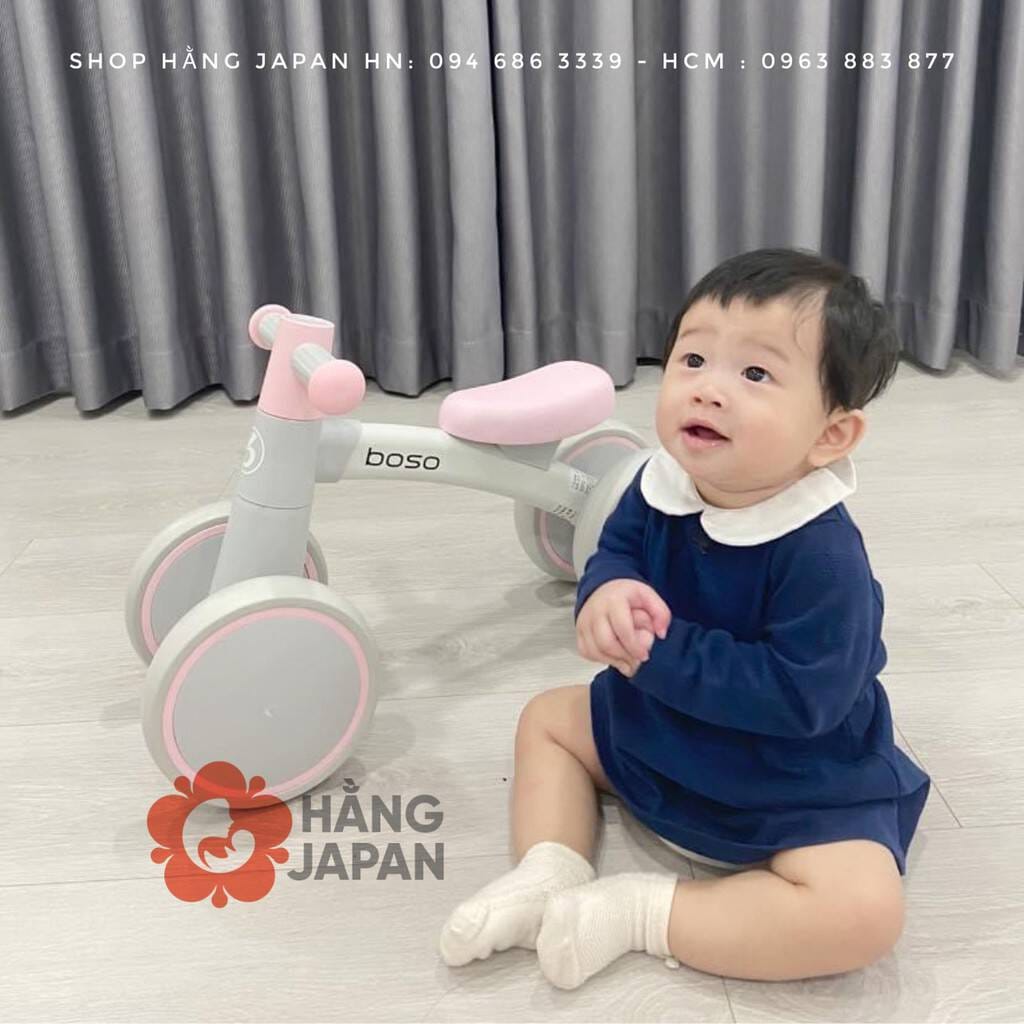 Bé trai trên chiếc xe chòi chân màu đỏ với mũ bảo hiểm và biểu cảm vui tươi