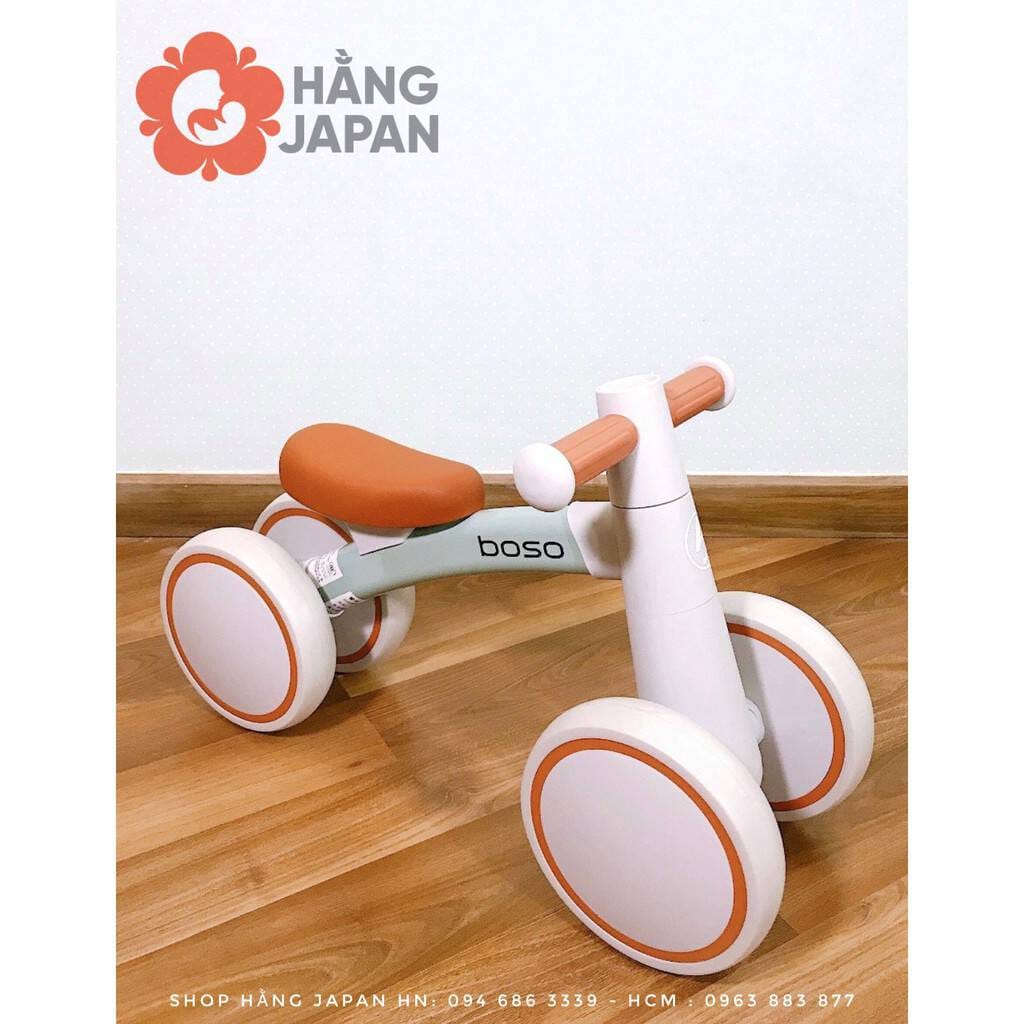 Cận cảnh bánh xe và chân của bé đang đẩy một chiếc xe chòi chân màu kem