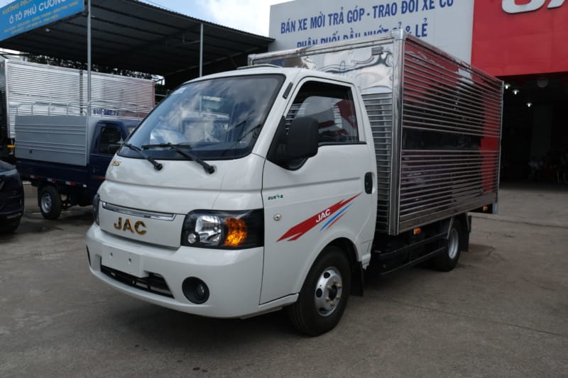 Một dãy xe tải JAC X150 mới với nhiều màu sắc và loại thùng khác nhau đang đỗ trong bãi, minh họa bảng **giá xe tải nhỏ 1.5 tấn** tương ứng với từng loại thùng
