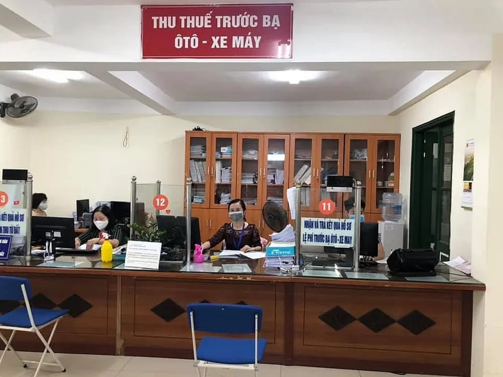 Một người đang làm thủ tục nộp lệ phí trước bạ cho xe máy điện tại quầy, có biên lai và giấy tờ trên bàn.