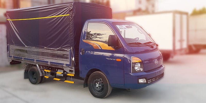 Xe tải Isuzu QKR77FE4 thùng mui bạt màu xanh dương đang đỗ, minh họa kiểu dáng thiết kế đặc trưng và hiện đại của dòng **xe tải nhỏ 1.5 tấn**